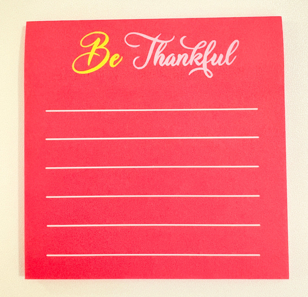 Red sticky note stack with 'Be Thankful' text on a beige background